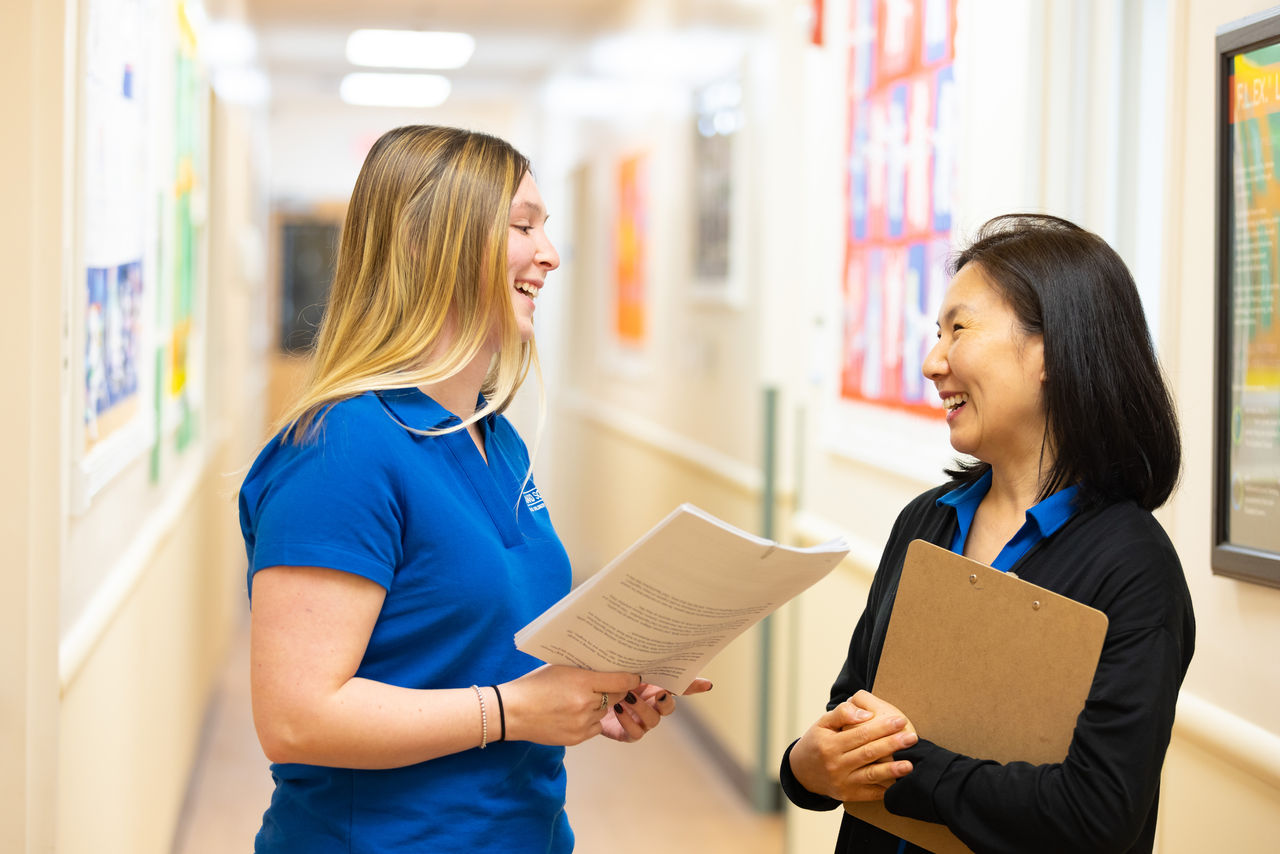 A Goddard School franchisee and teacher chatting in the hallway of the school