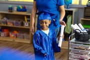 child dressed in a graduation gown